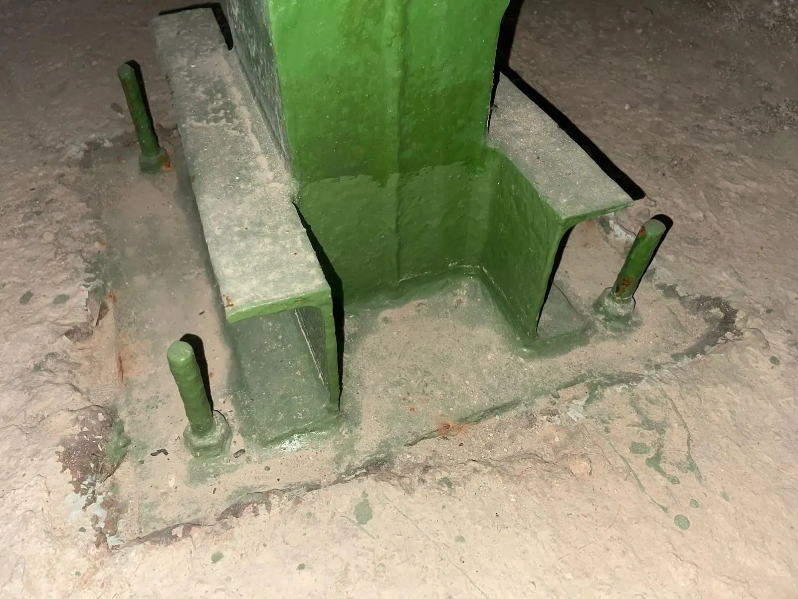 Placa de anclaje de pilar metálico pintada de verde en buen estado