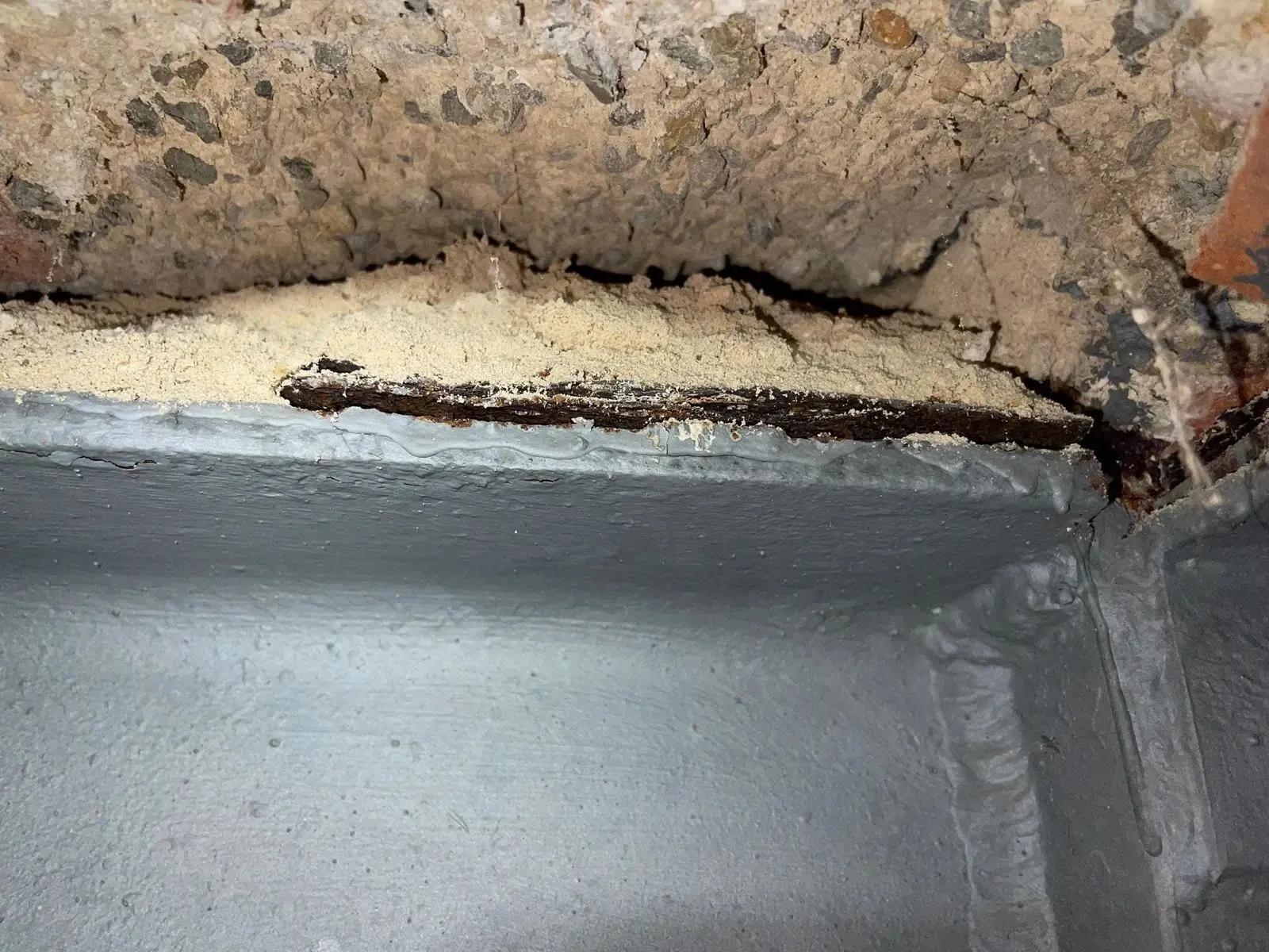 Ala de una viga metálica con óxido laminar bajo una fábrica de ladrillo
