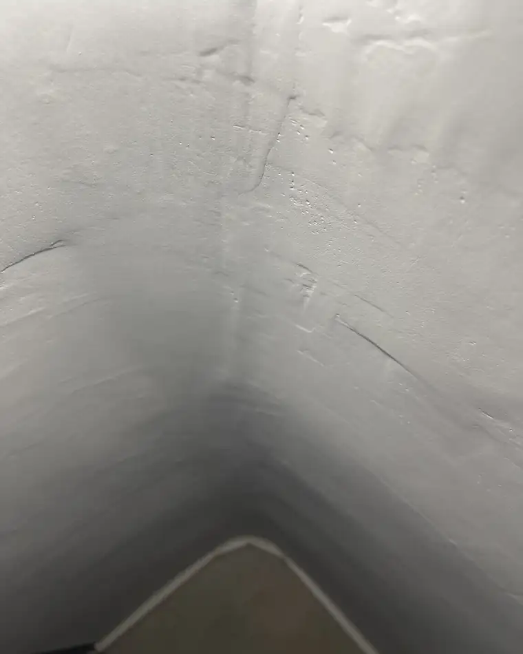 Rincón de pared con el enlucido irregular visto con luz rasante
