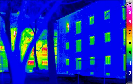 Termografía de dos edificios: el aislado se ve frío y el que no tiene aislamiento pierde calor por toda la fachada