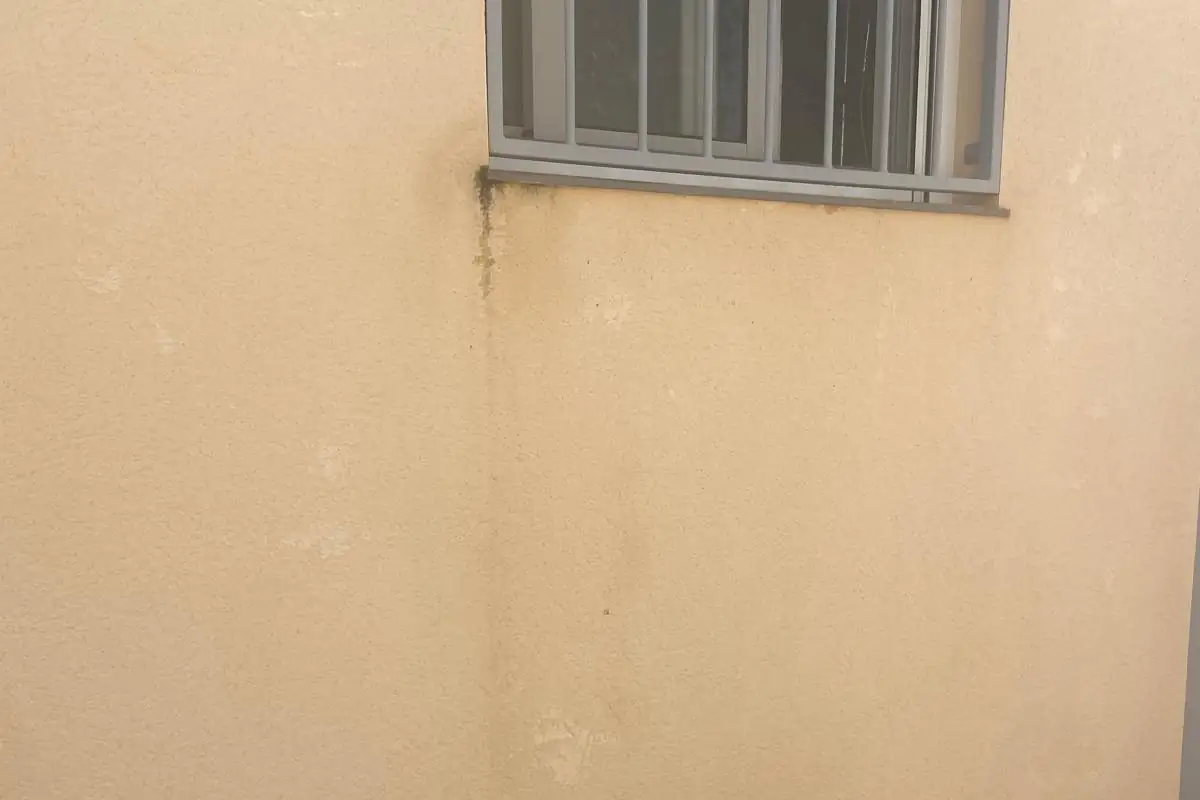 Fachada de vivienda con humedad en la base del muro